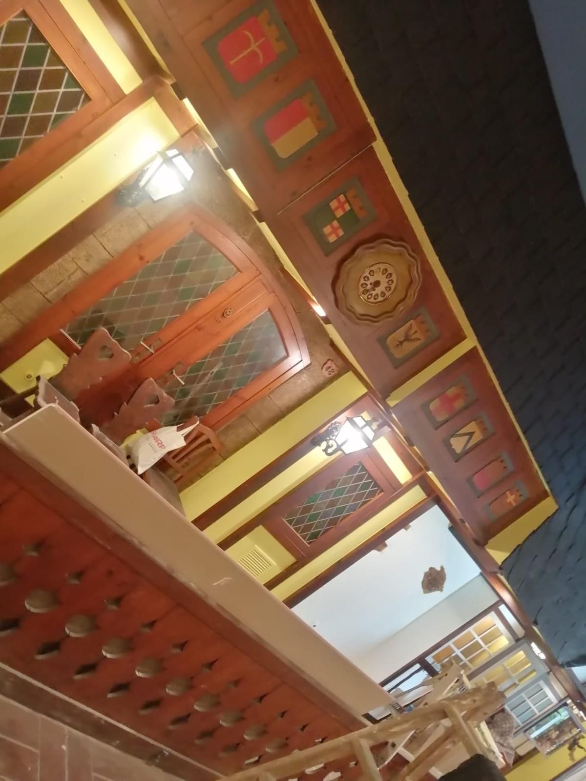 Piscina azul brillante en el patio trasero, junto a un patio con un cubo y herramientas en primer plano.