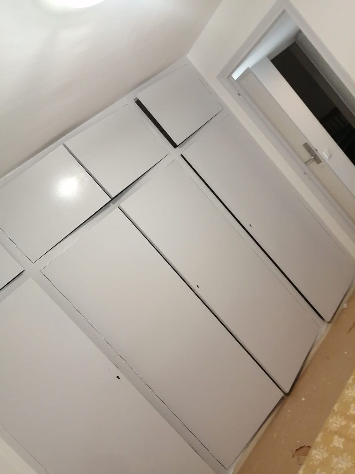 Puertas blancas de armario empotrado en una vista oblicua dentro de una habitación luminosa.