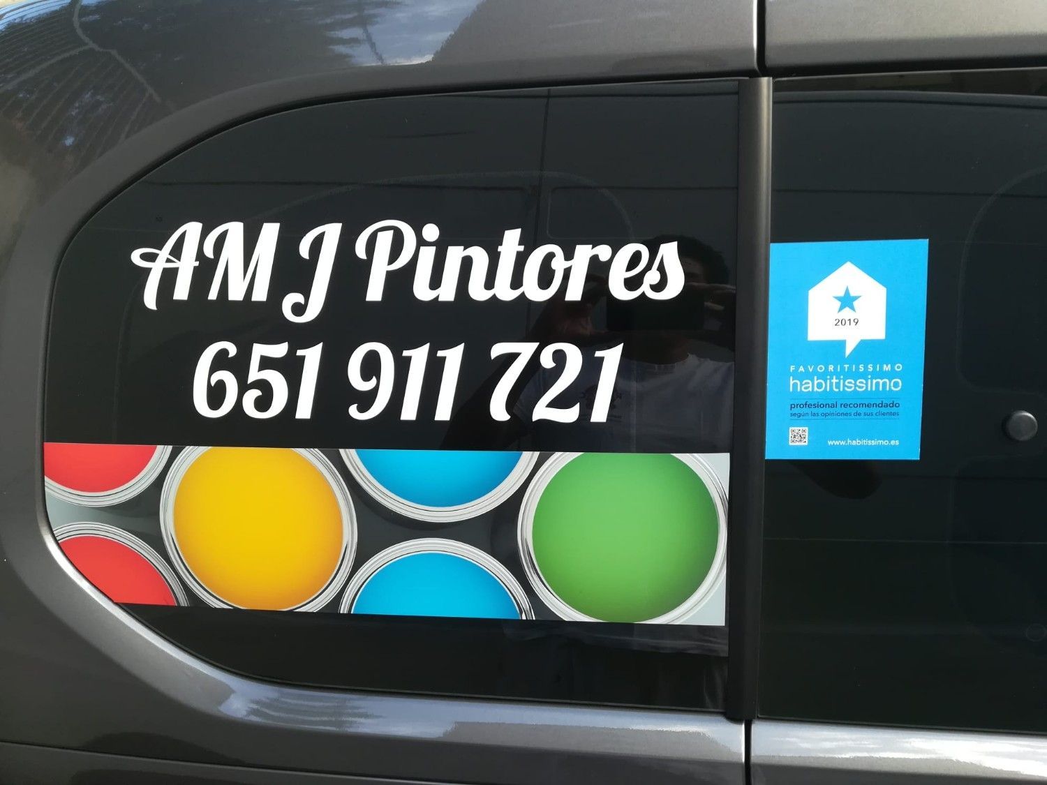 Letrero de AM J Pintores en el vehículo, con el número de teléfono 651 911 721 y círculos de pintura de colores.