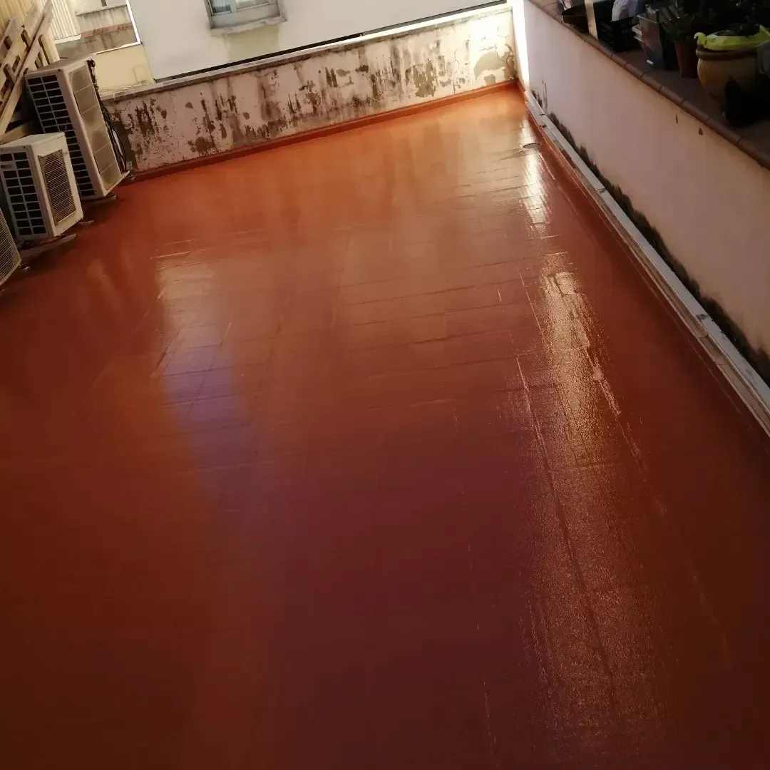 Terraza vacía pintada de naranja en la azotea, con suelo mojado y reflectante y paredes blancas.