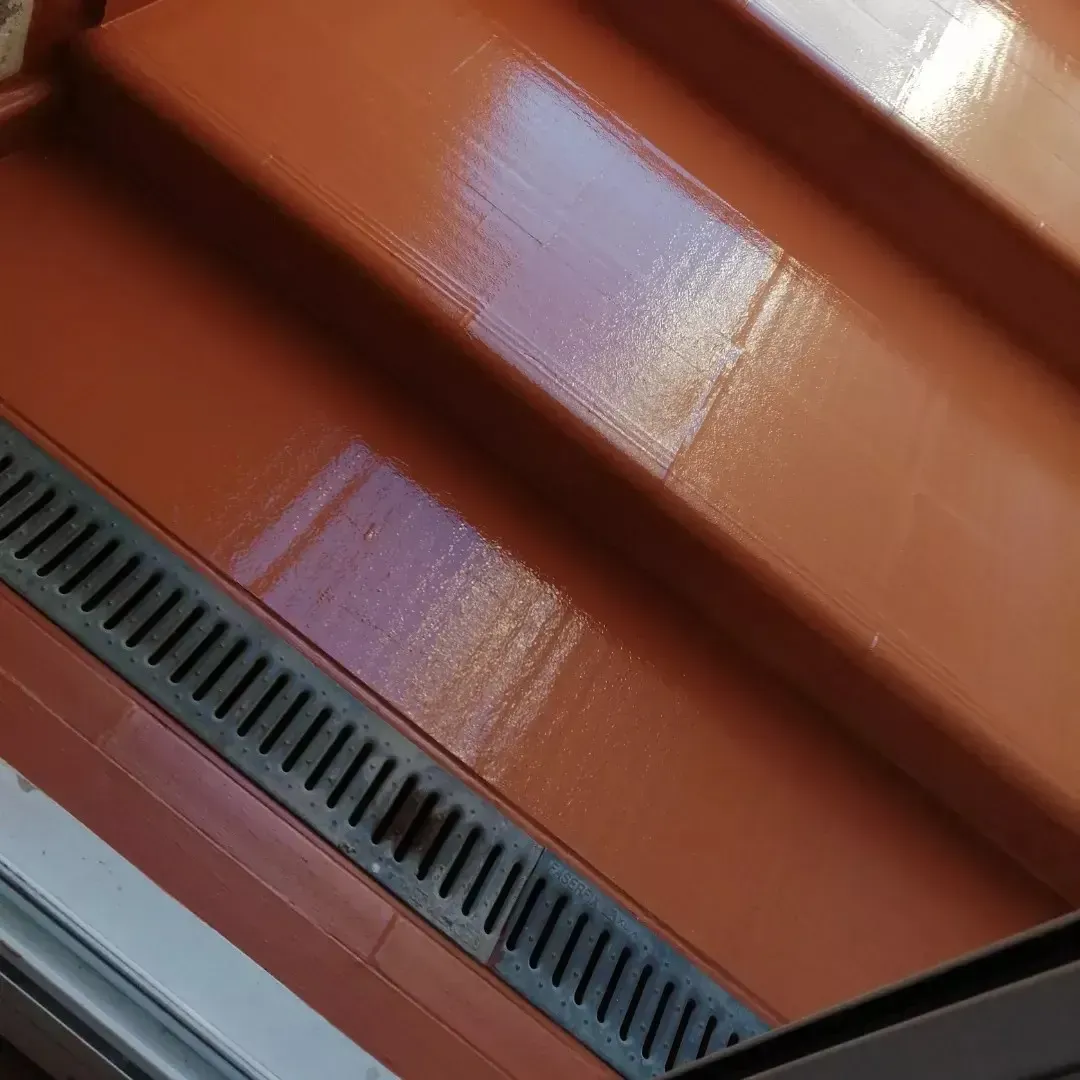 Paneles de techo de metal pintados de rojo con un canalón oscuro a lo largo del borde.