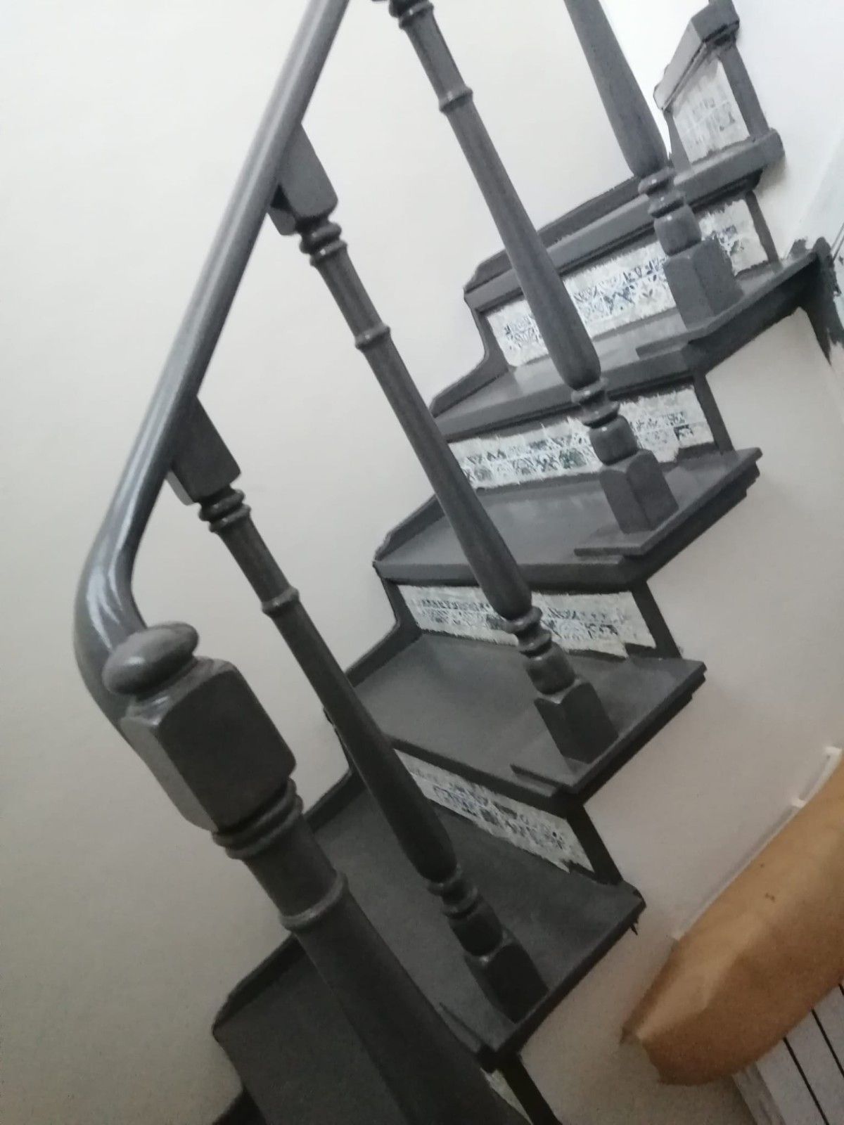 Escalera negra con barandilla de metal y escalones estampados en el interior de una vivienda.