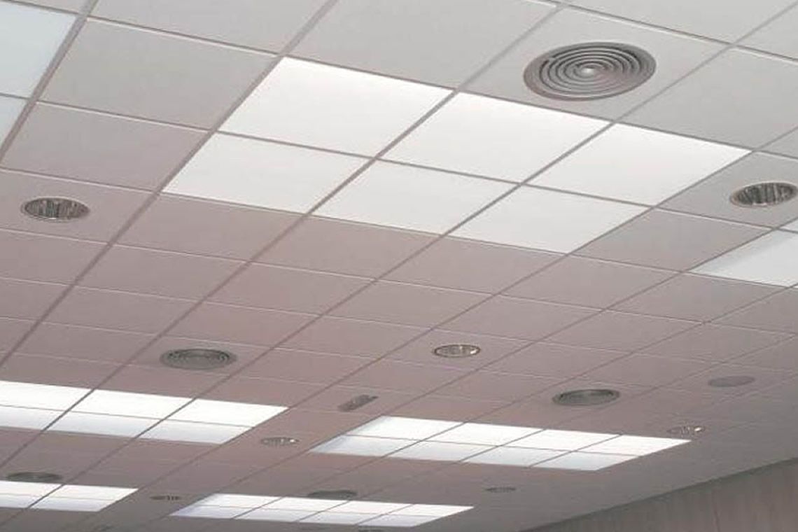 Techo de oficina blanco con iluminación empotrada y rejillas de ventilación.