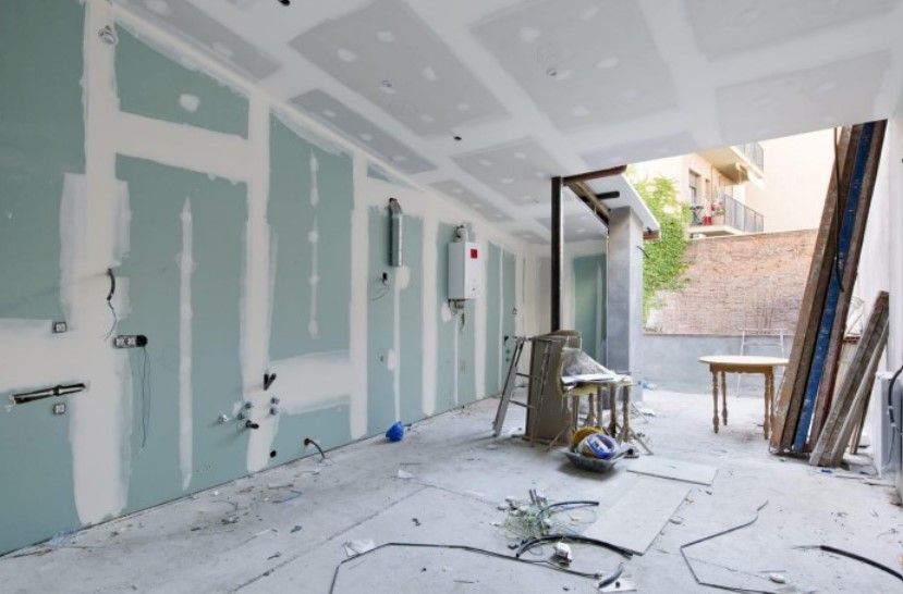 Interior en construcción, con paneles de yeso en paredes y techo. Cableado eléctrico expuesto.