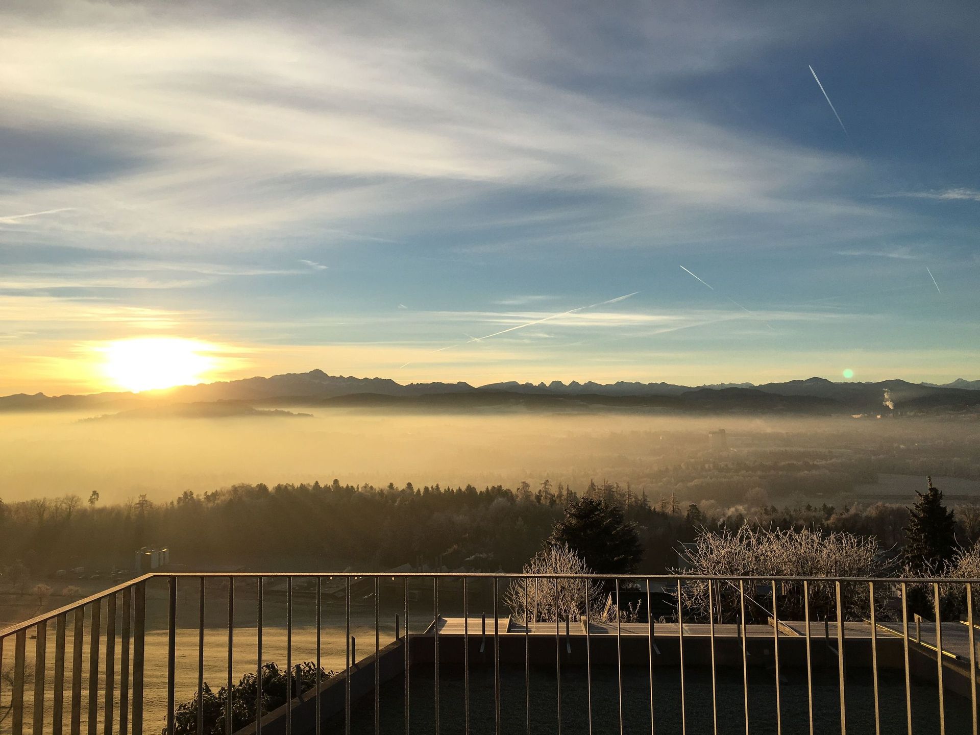 Ein Balkon mit Blick auf ein nebliges Tal, durch dessen Wolken die Sonne scheint