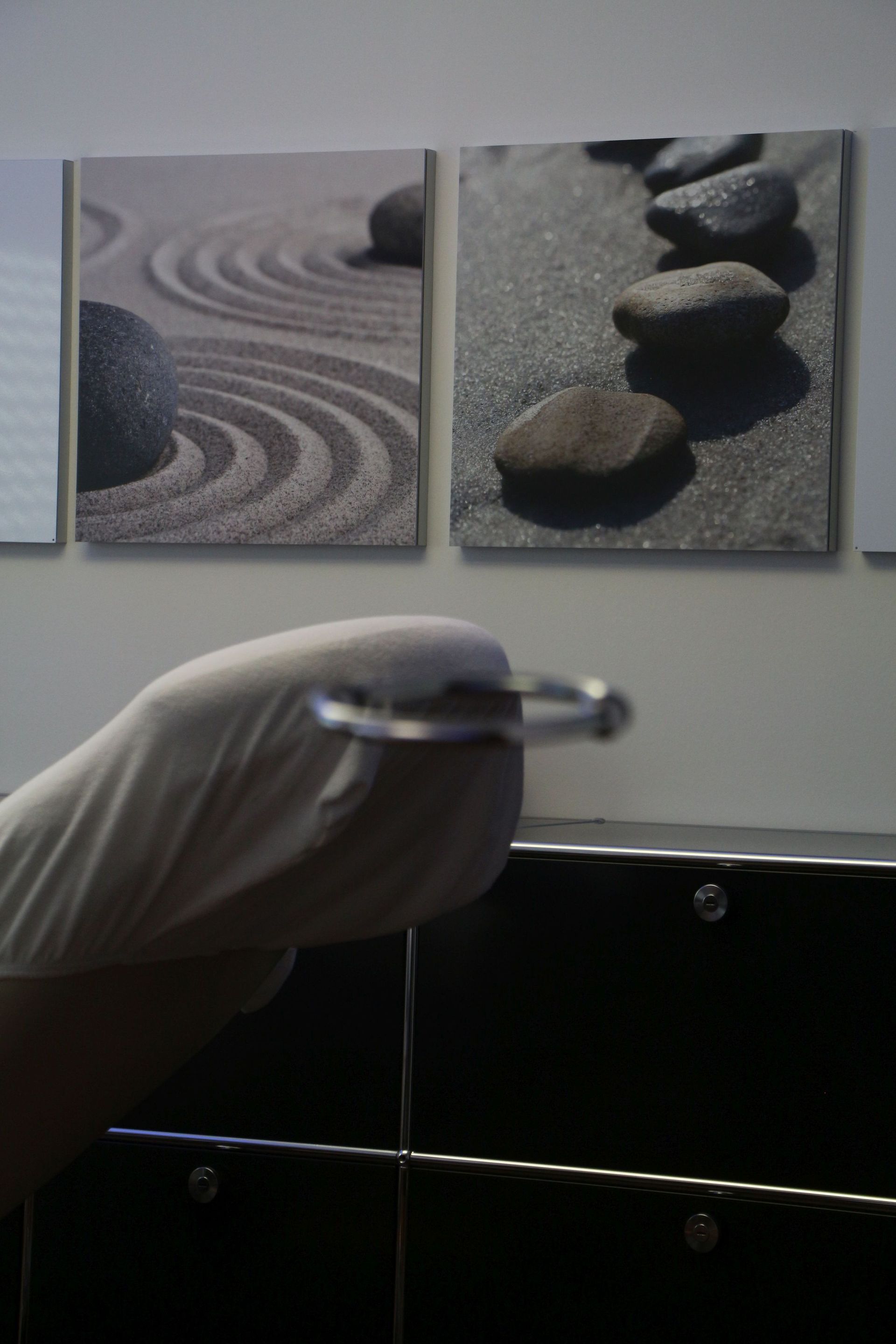 Eine Person hält vor einem Gemälde mit Felsen einen Metallgegenstand in der Hand.