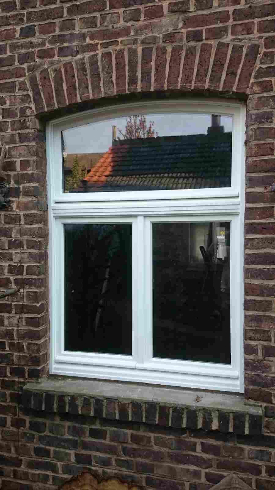 An der Seite eines Backsteingebäudes befindet sich ein weißes Fenster.