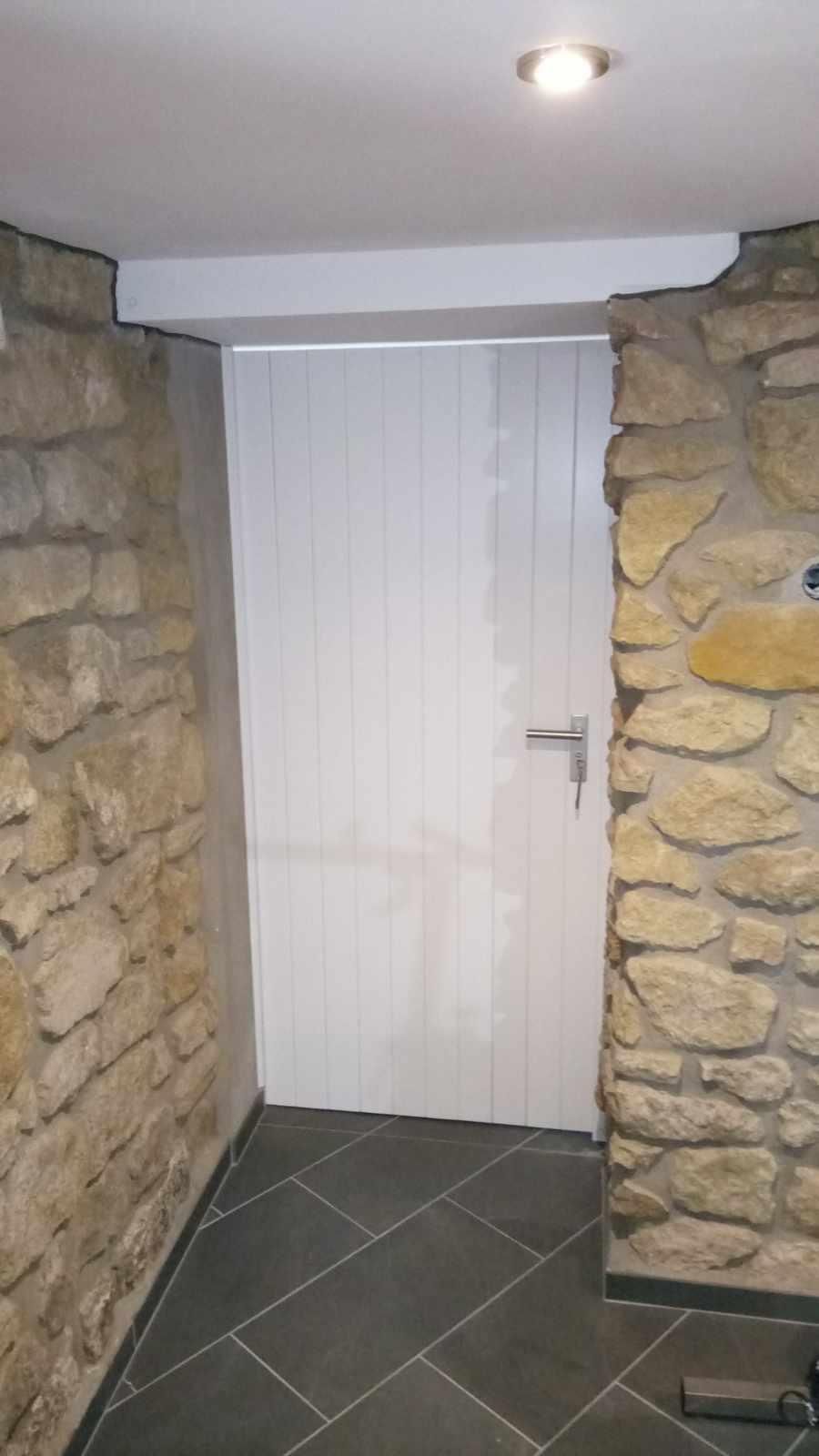 Ein Flur mit einer Steinwand und einer weißen Tür.