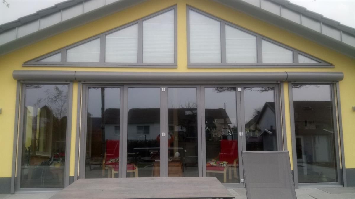 Ein gelbes Haus mit vielen Fenstern und einem Tisch davor.