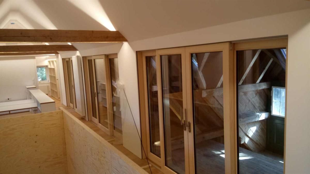 Ein Raum mit vielen Fenstern und einer Treppe im Hintergrund.