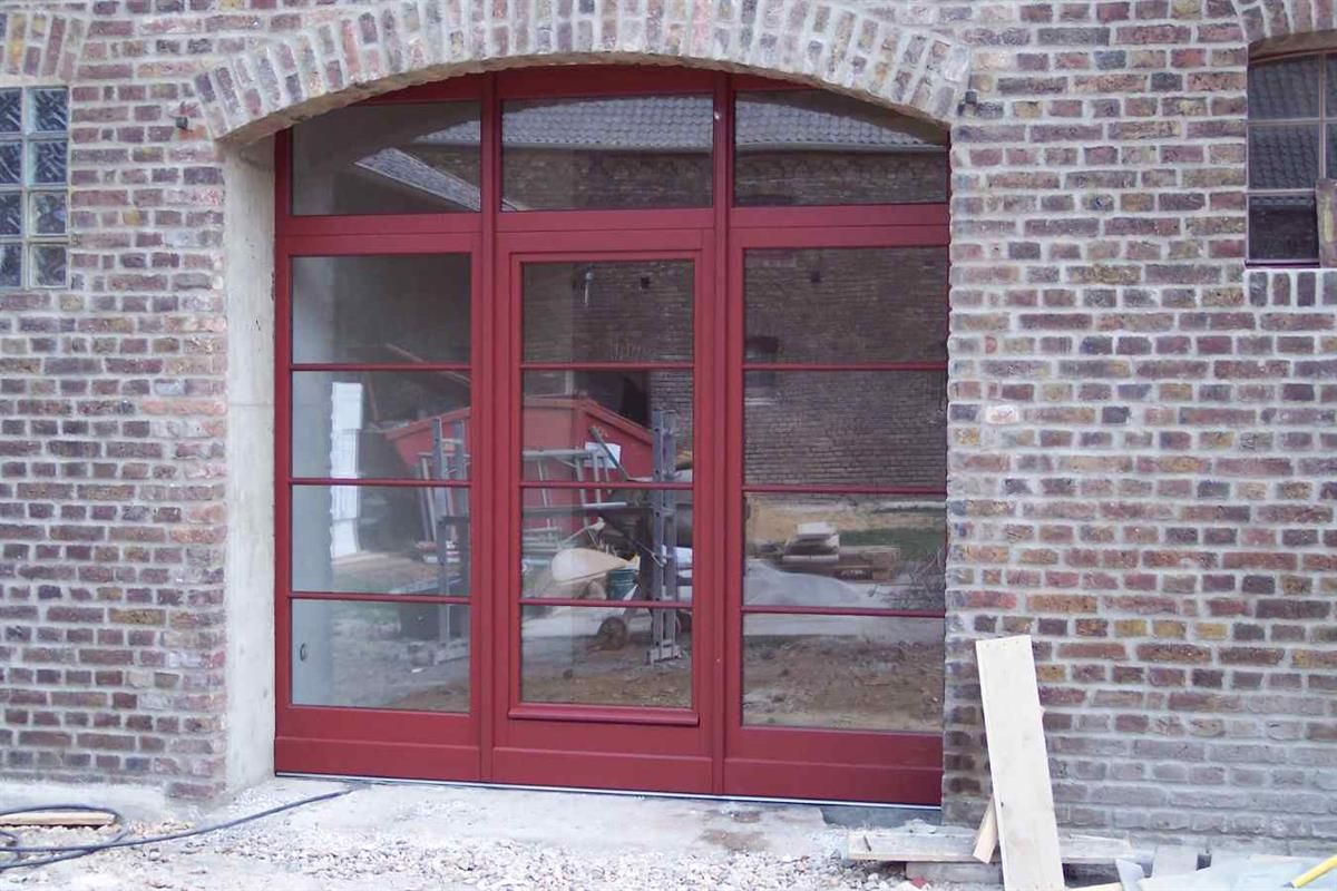 Vor einem Backsteingebäude befindet sich eine rote Tür.