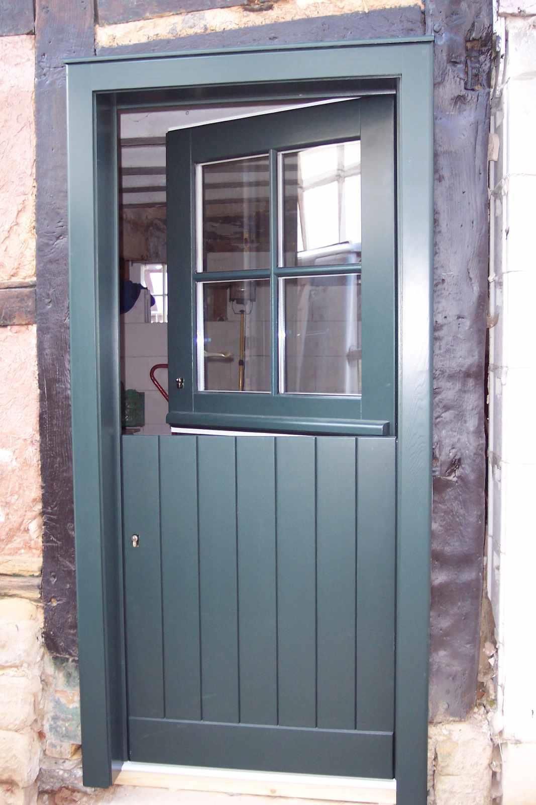 Eine grüne Tür mit einem Glasfenster geht zu einem Raum hin offen.