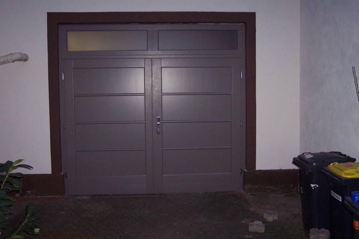 Ein Garagentor mit einem Fenster und einem Mülleimer davor