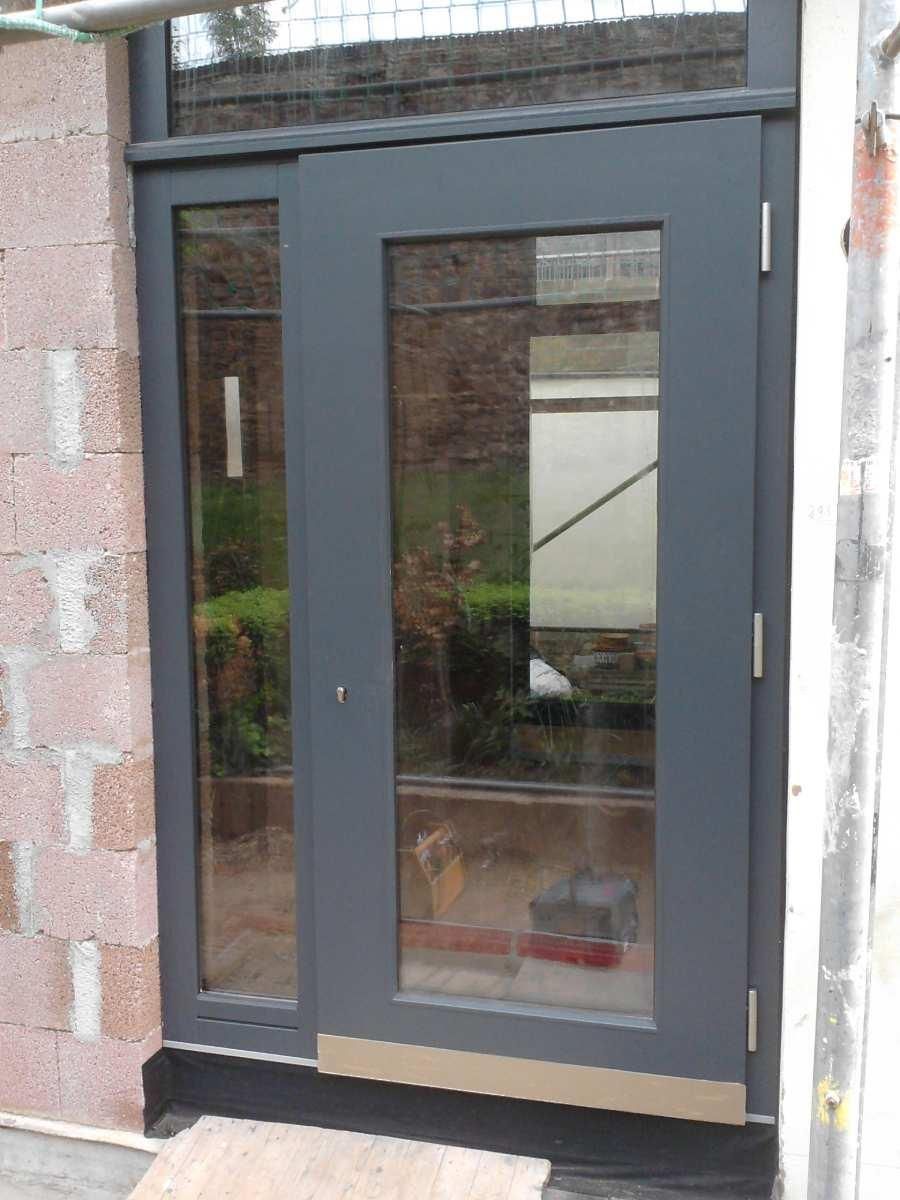 In einer Backsteinmauer sitzt eine Tür mit viel Glas.