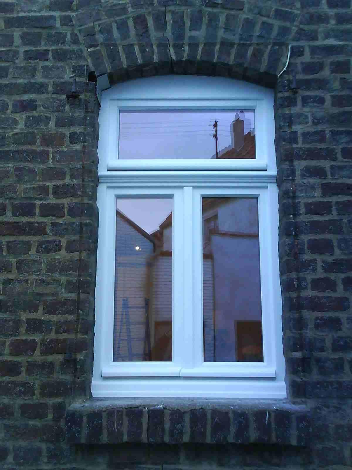 An der Seite eines Backsteingebäudes befindet sich ein weißes Fenster.