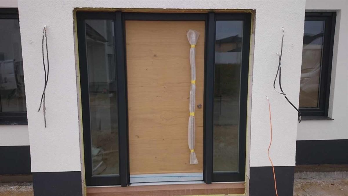 An der Seite eines Gebäudes befindet sich eine Holztür mit schwarzem Rahmen.