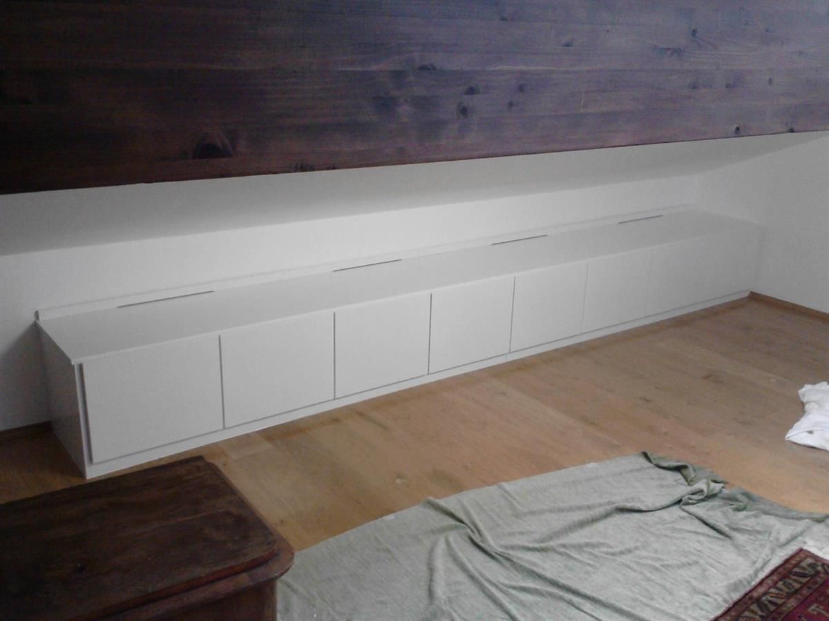 Ein Wohnzimmer mit Holzboden und weißen Schränken