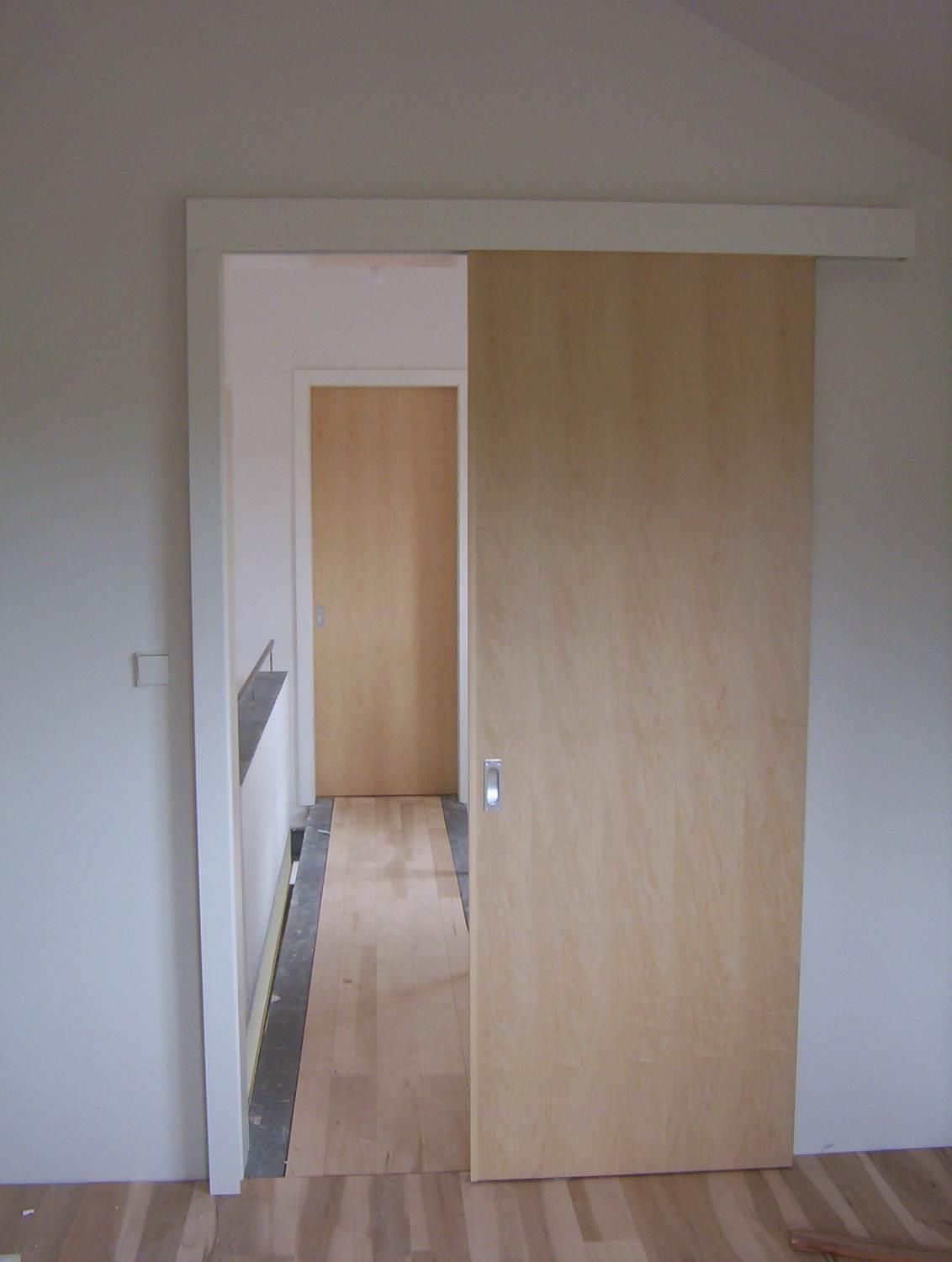 Eine hölzerne Schiebetür öffnet sich zu einem Flur