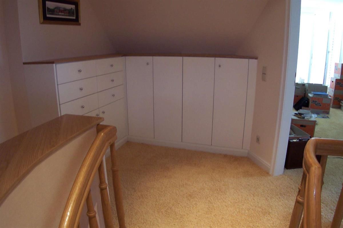 Eine Treppe führt hinauf zu einem Raum mit weißen Schränken