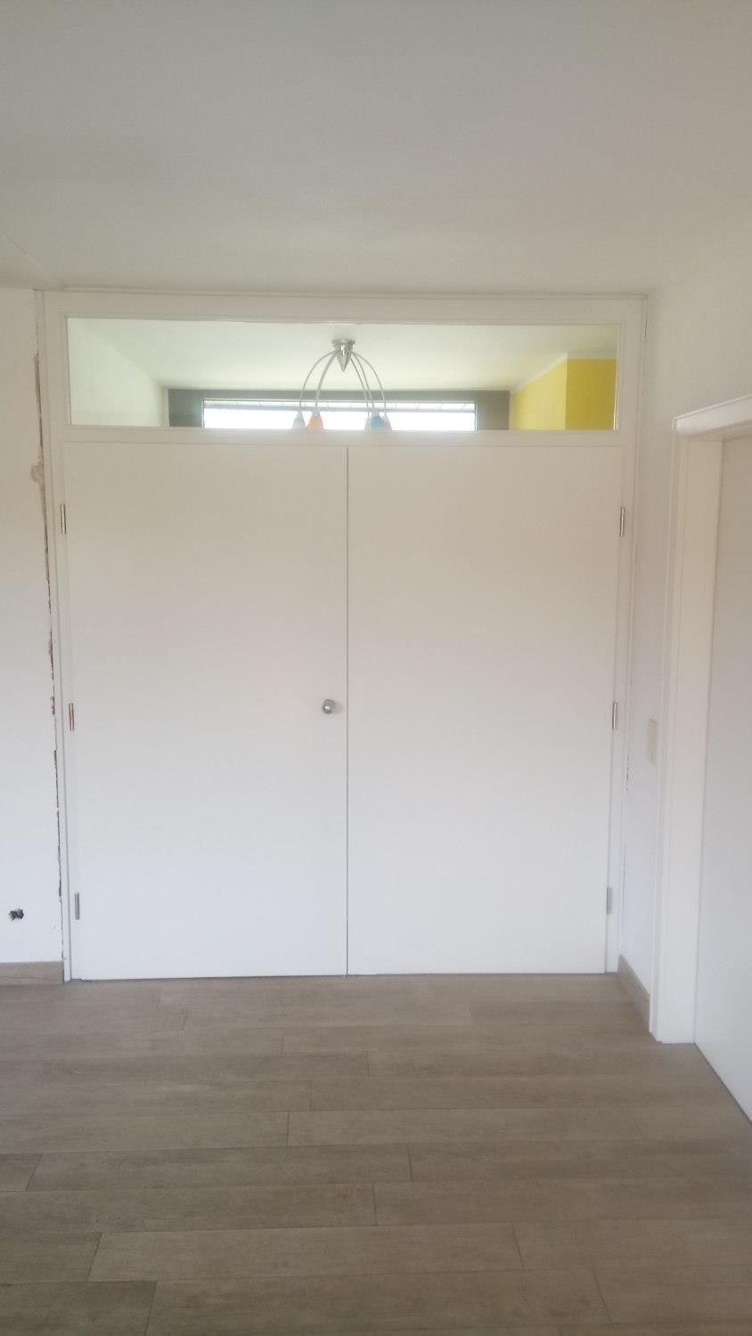 Ein leerer Raum mit weißen Wänden und Holzboden.