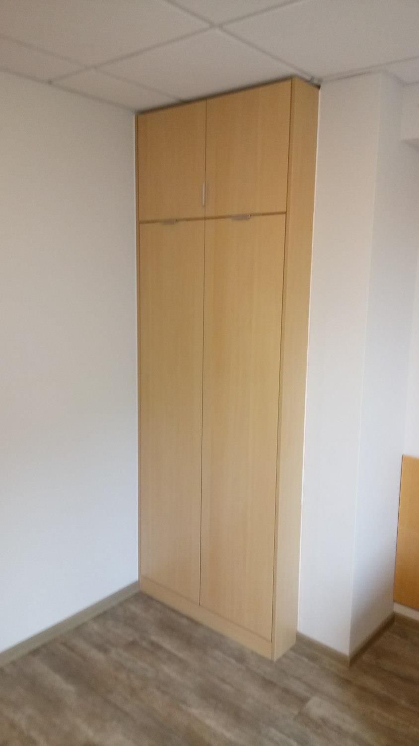 Ein leerer Raum mit einem großen Holzschrank in der Ecke.