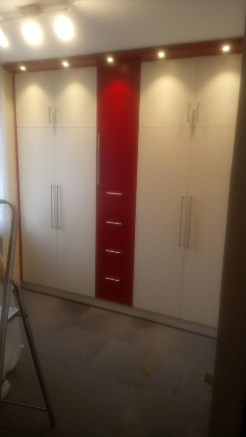 Ein Raum mit roten und weißen Schränken und einer Leiter.