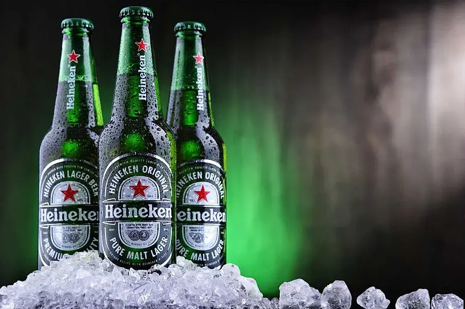 Tres botellas de cerveza Heineken en hielo, etiquetas verdes y negras.