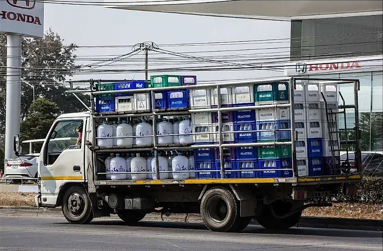 Un camión lleno de cubos y cajas está estacionado al costado de la carretera.