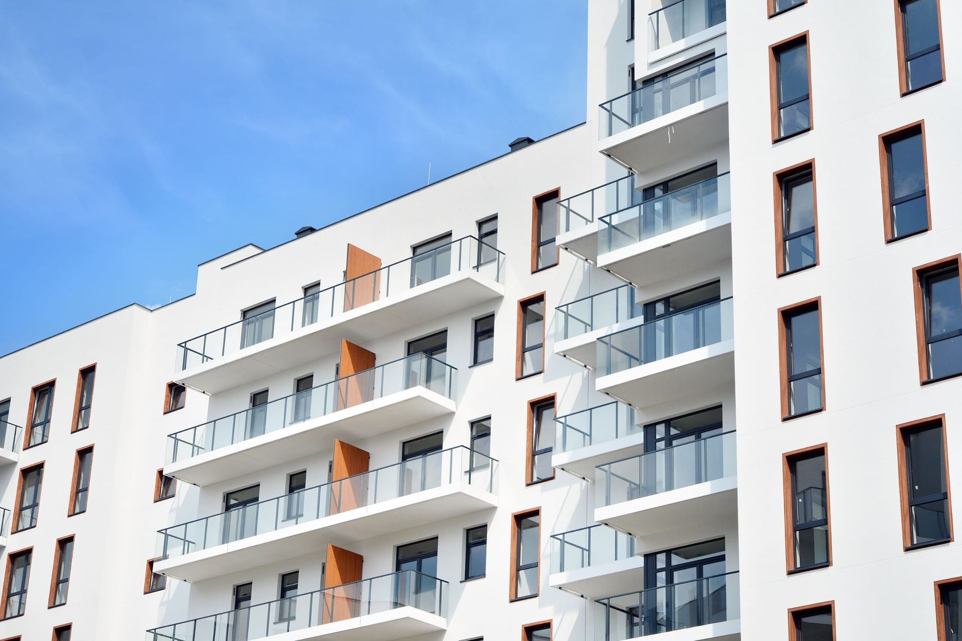Un gran edificio de apartamentos blanco con balcones y ventanas contra un cielo azul.