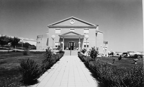 Una fotografía en blanco y negro de un gran edificio con una pasarela que conduce a él.