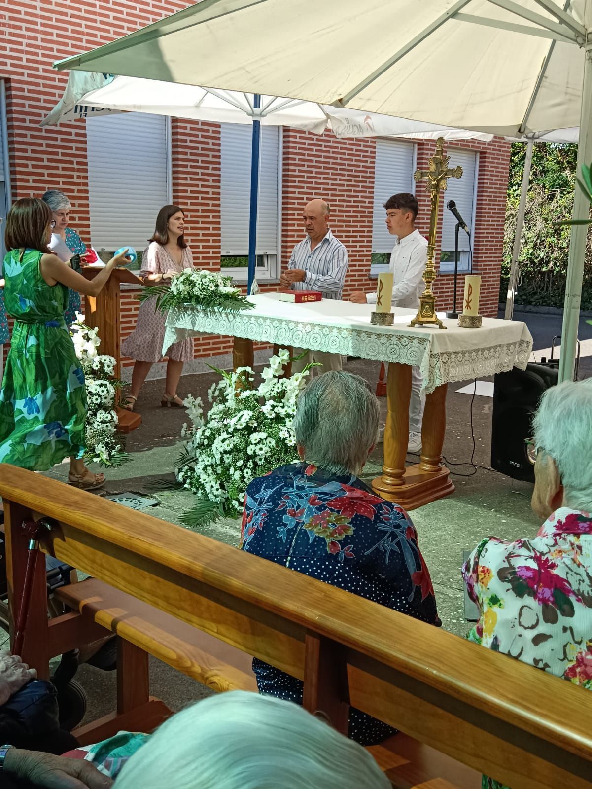 Una mujer con un vestido verde está parada frente a una mesa con flores.