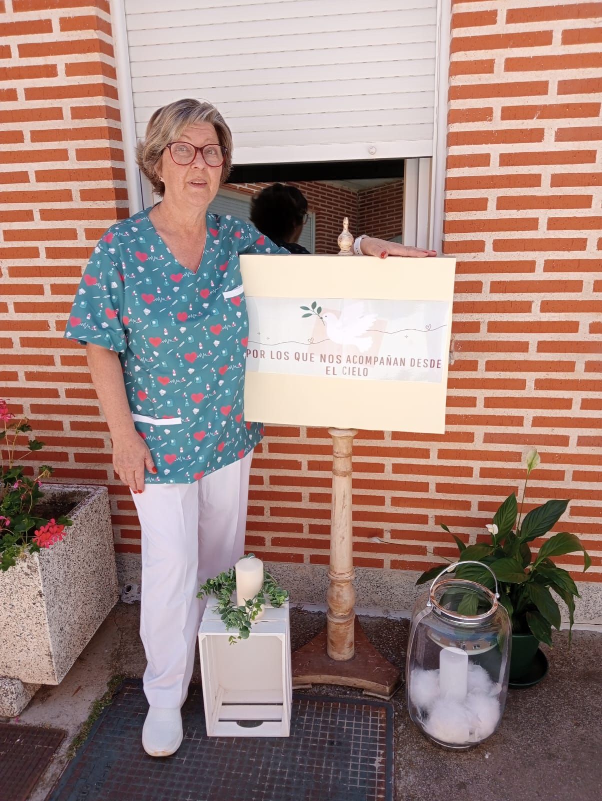 Una mujer está parada frente a un edificio de ladrillos sosteniendo un cartel que dice