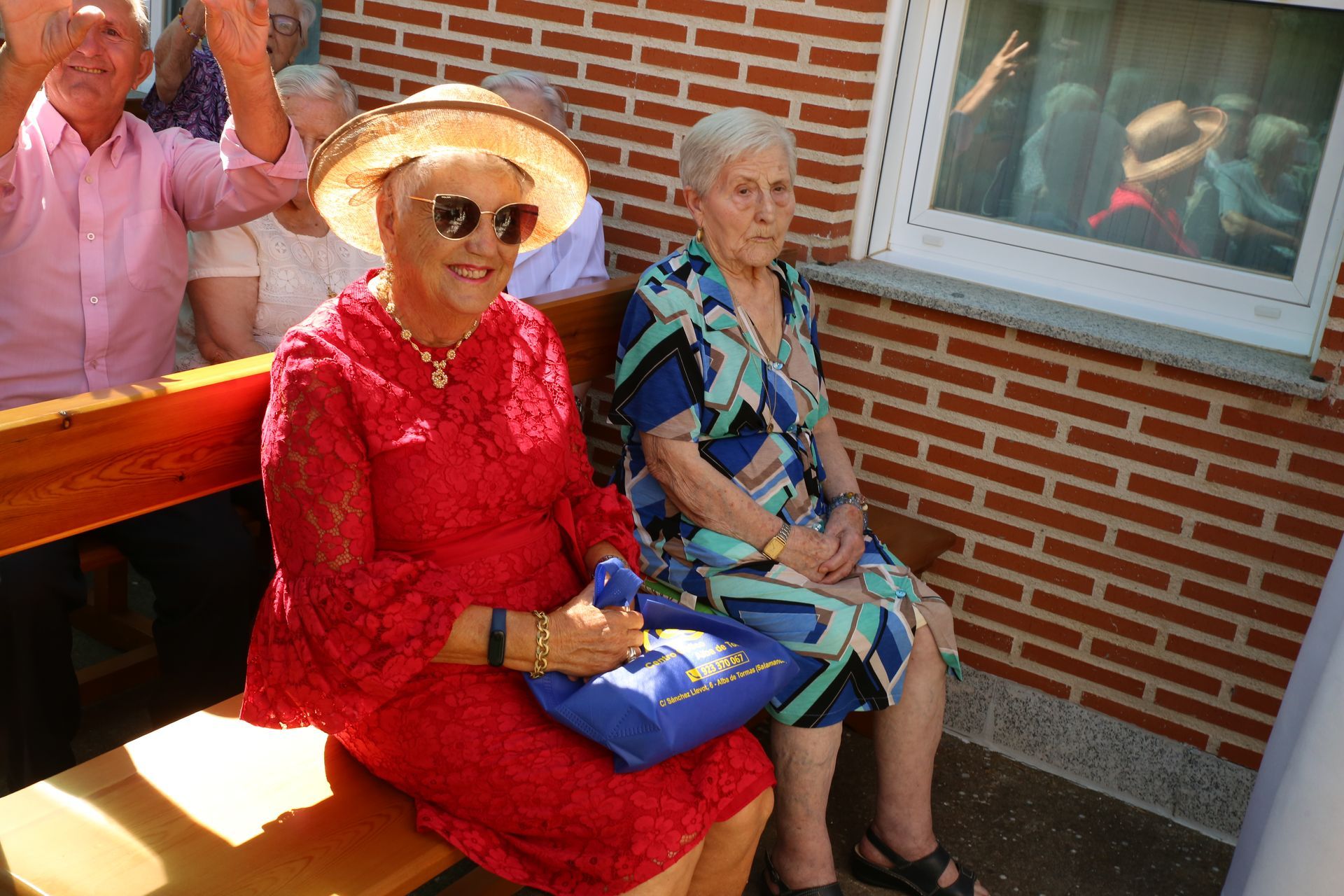 Una mujer con un vestido rojo se sienta junto a otra mujer con un vestido azul.