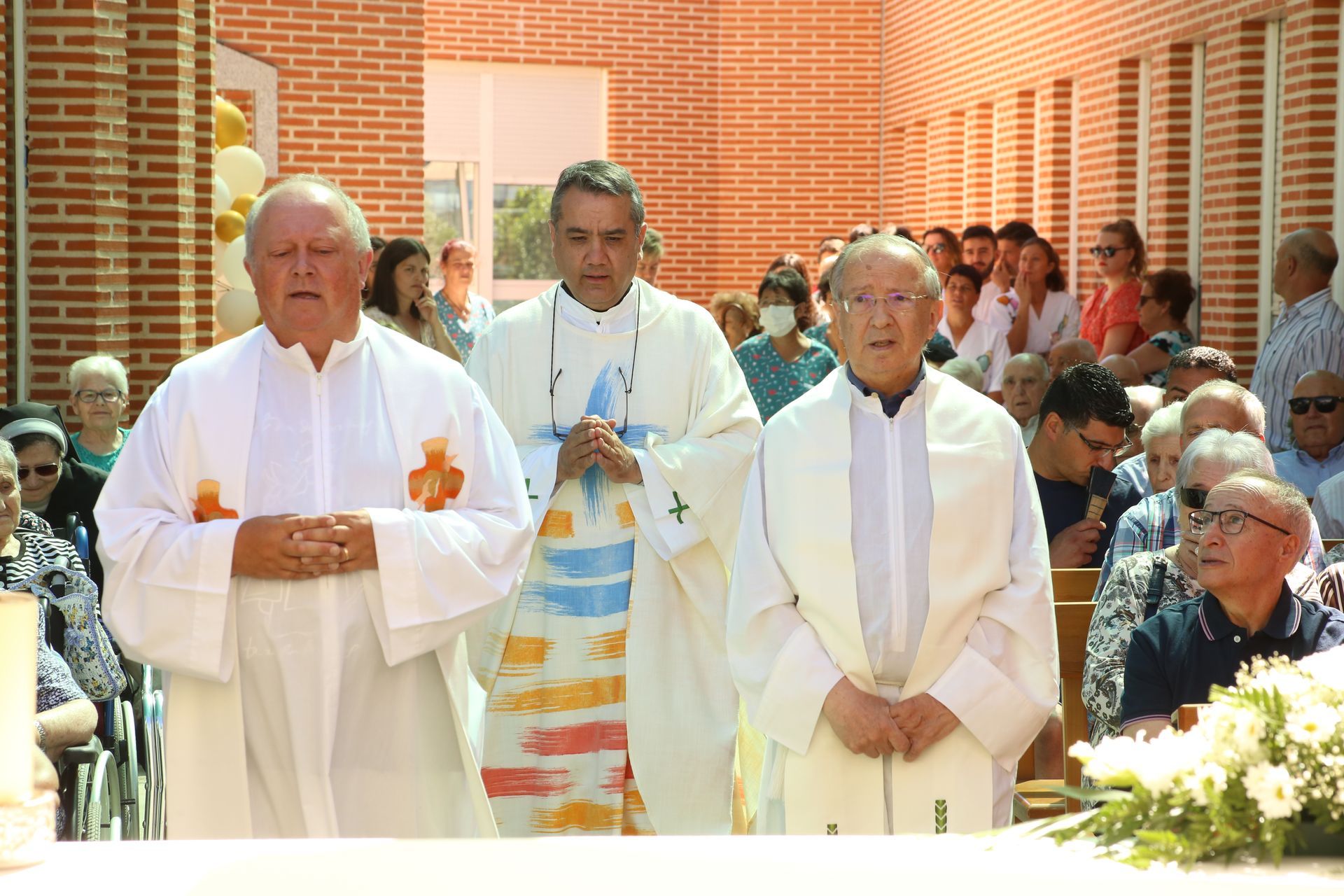 Un grupo de sacerdotes están de pie frente a una multitud.