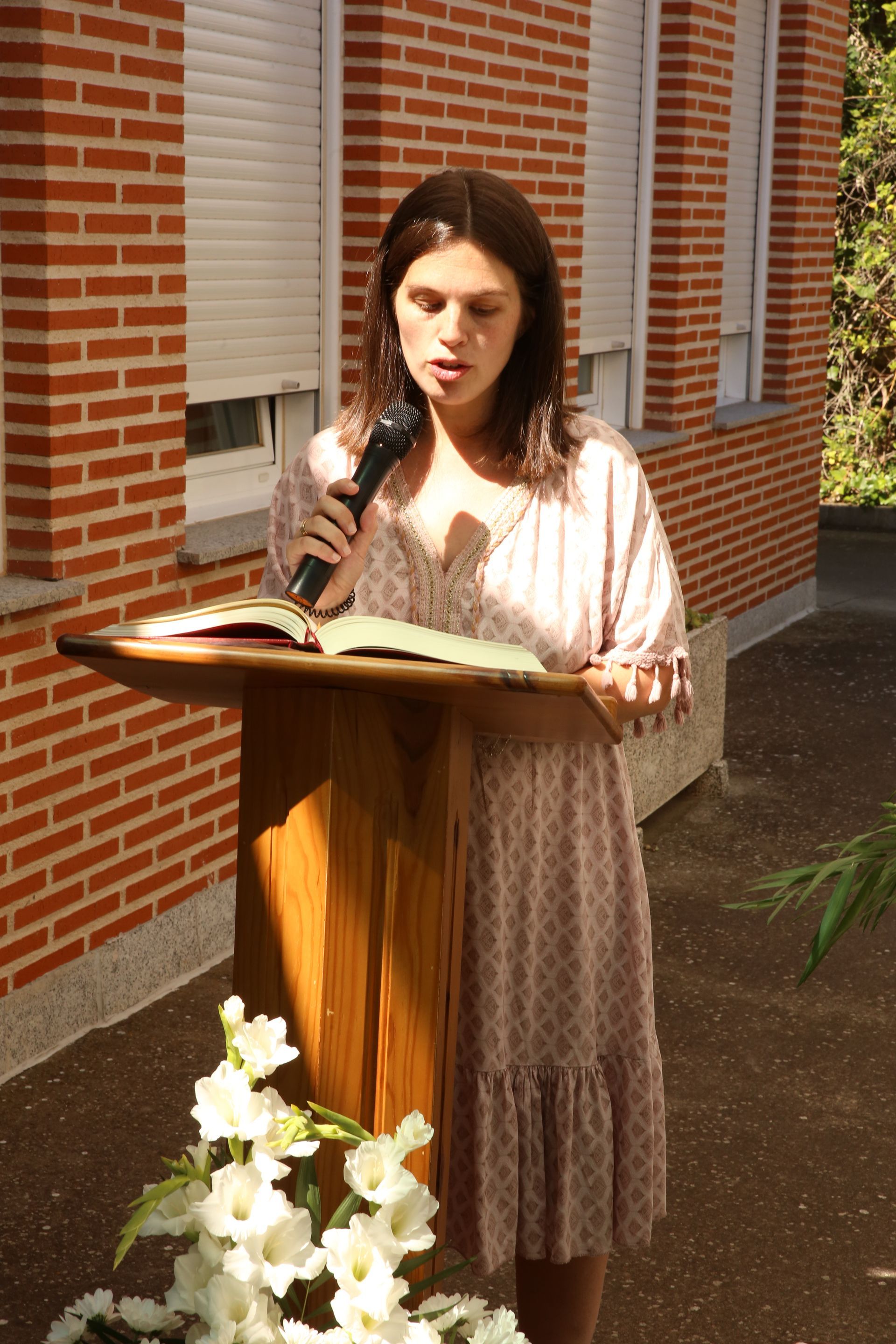 Una mujer está parada en un podio sosteniendo un micrófono y una Biblia.