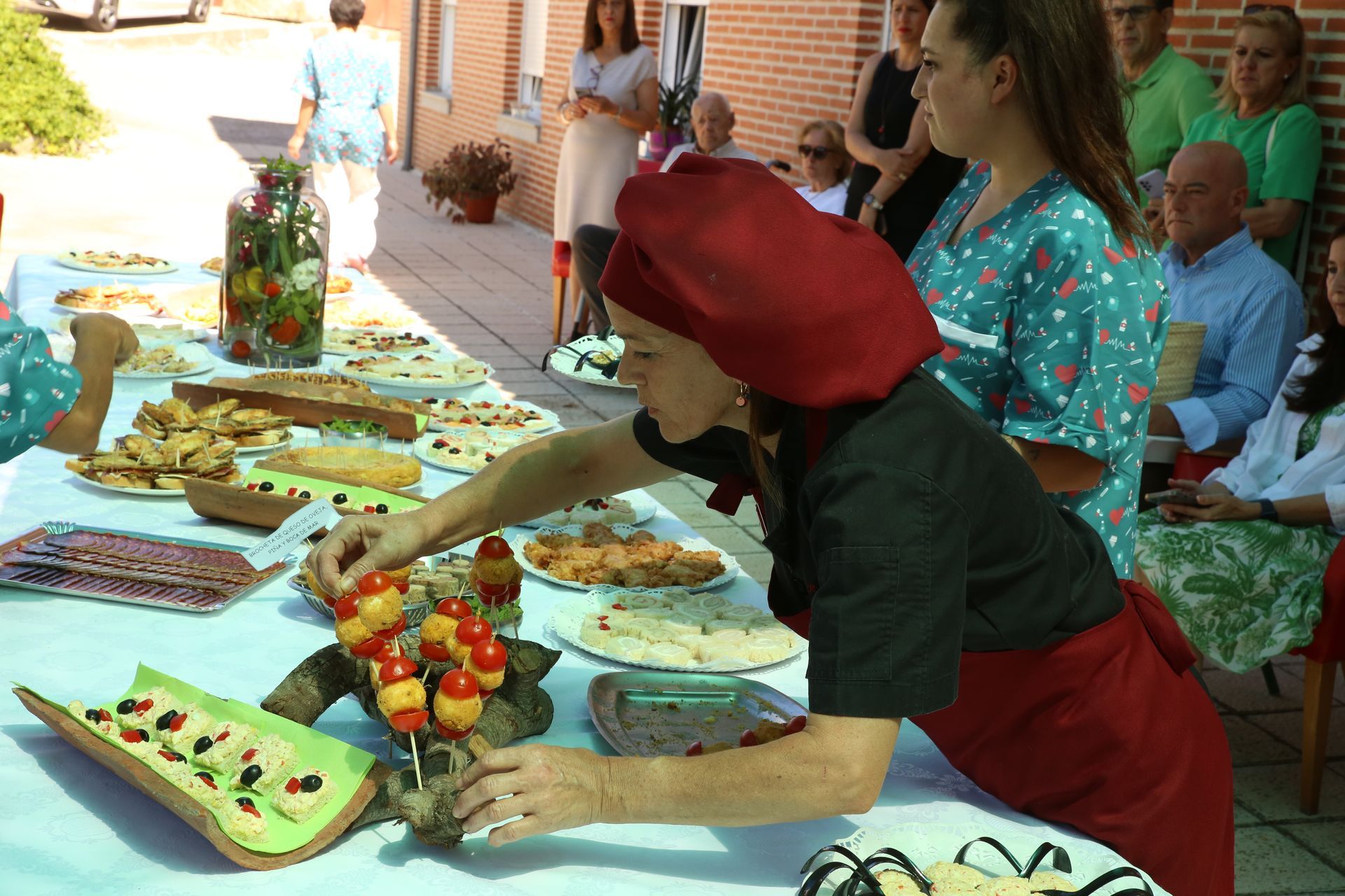 Una mujer con un sombrero rojo está preparando comida en una mesa.