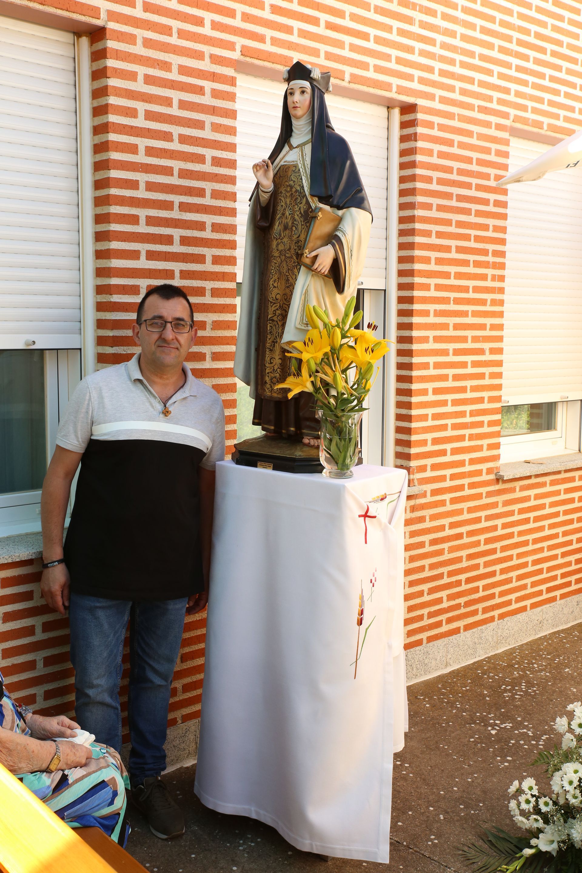 Un hombre está de pie junto a una estatua de una mujer frente a un edificio de ladrillos.
