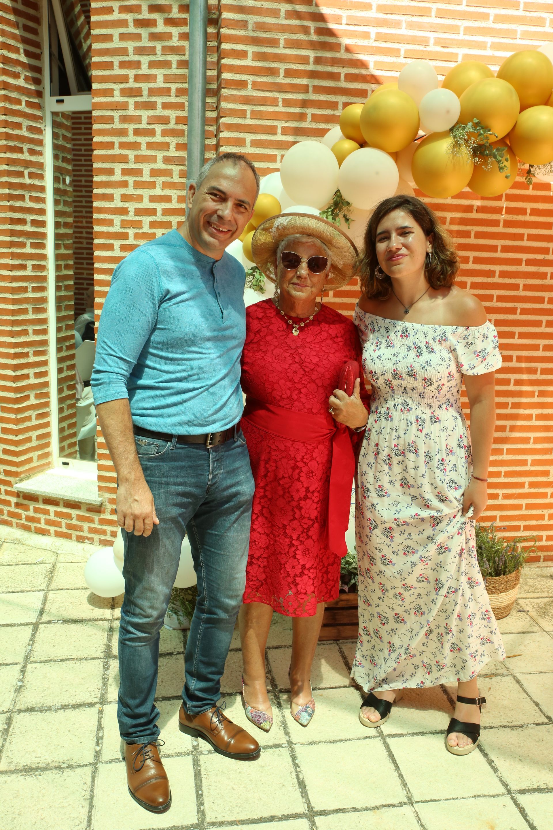 Tres personas posando para una foto frente a una pared de ladrillos.