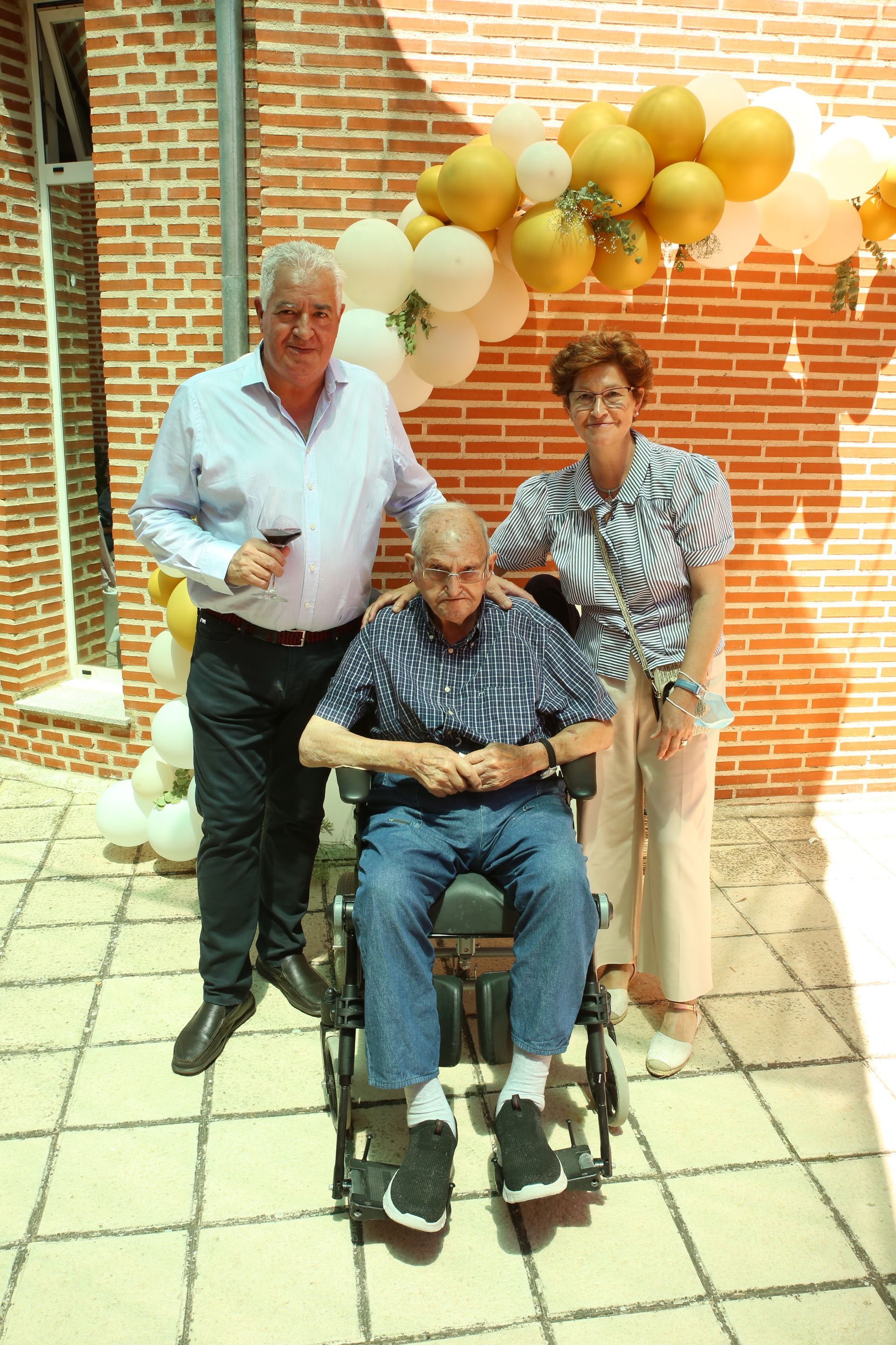 Un hombre en silla de ruedas posa para una fotografía con otras dos personas.