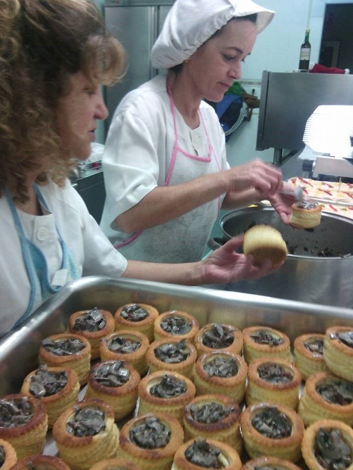 Dos mujeres están trabajando en una cocina preparando comida.