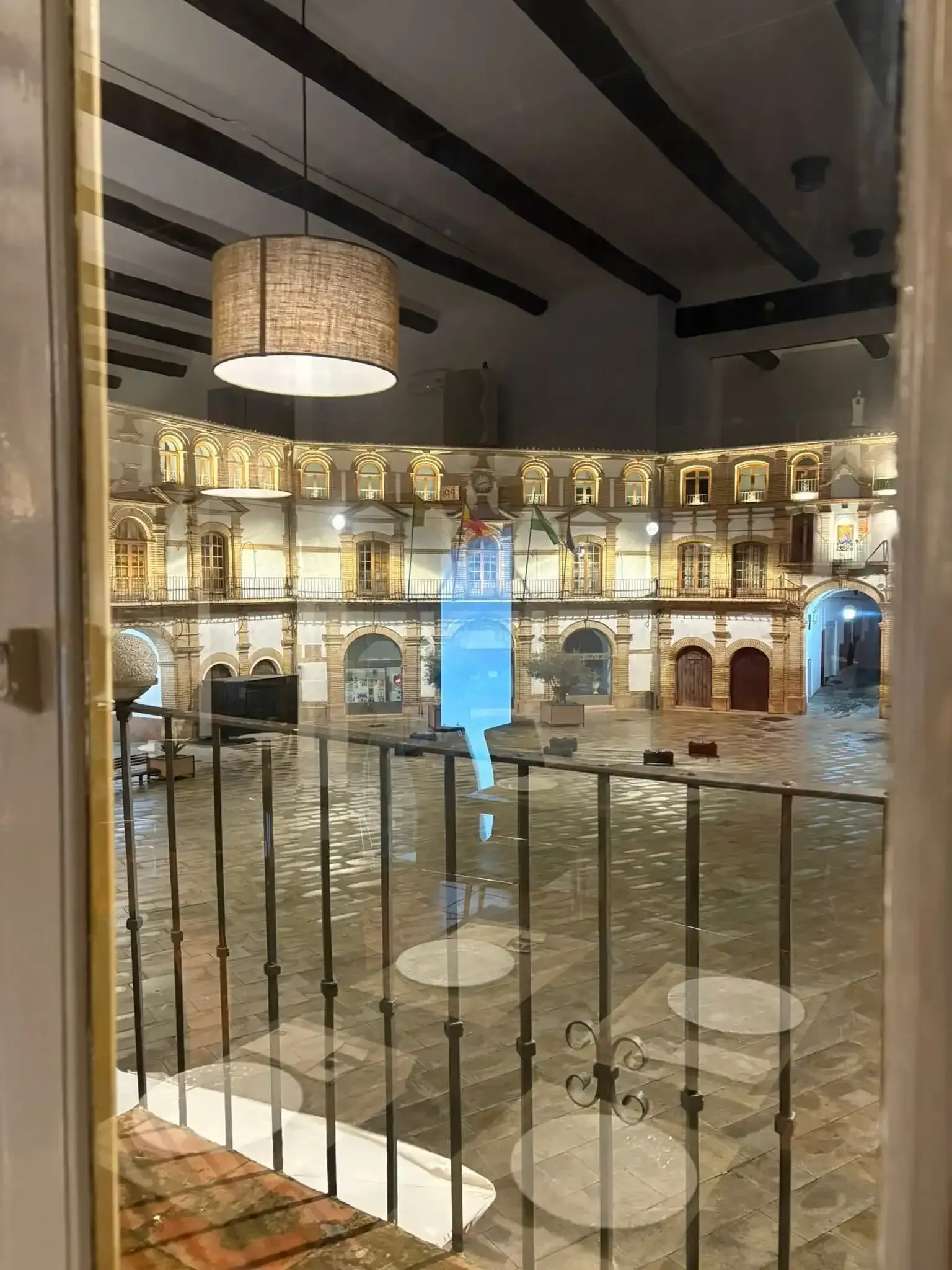 Vista desde un balcón interior de un patio histórico iluminado con arcos 