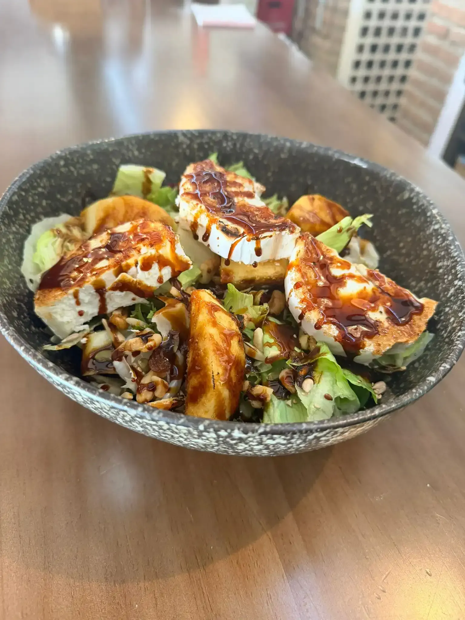 Ensalada con pollo a la parrilla y aguacate sobre una mesa de madera.