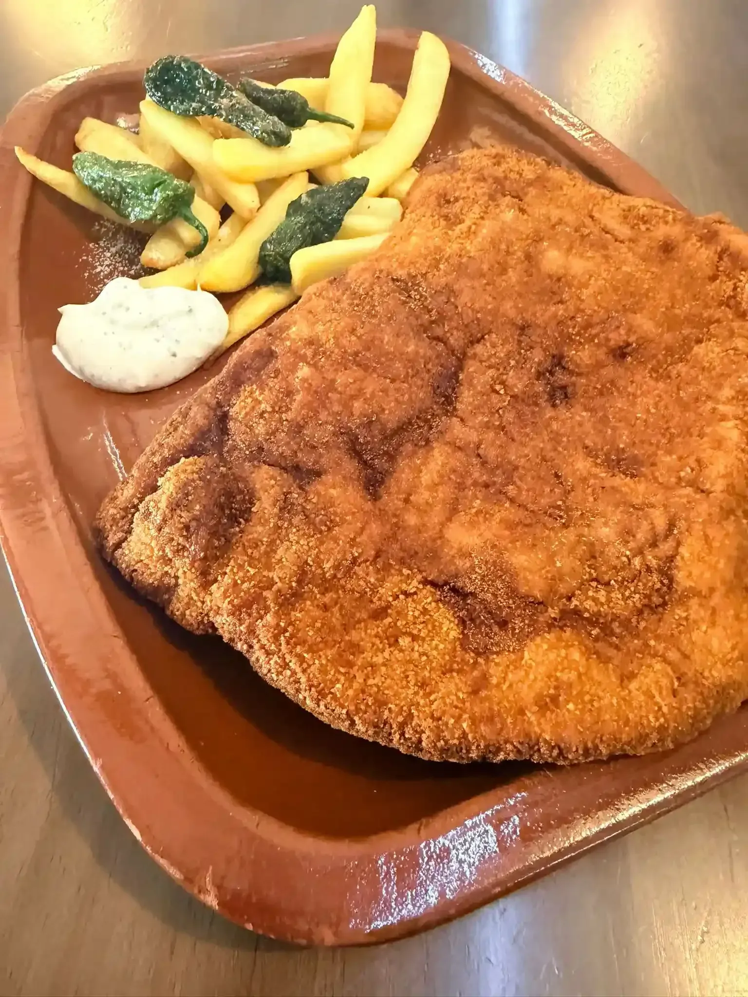 Chuleta empanizada frita con papas fritas y brócoli en un plato de bandeja marrón.