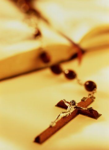 Terço com crucifixo sobre um livro aberto.