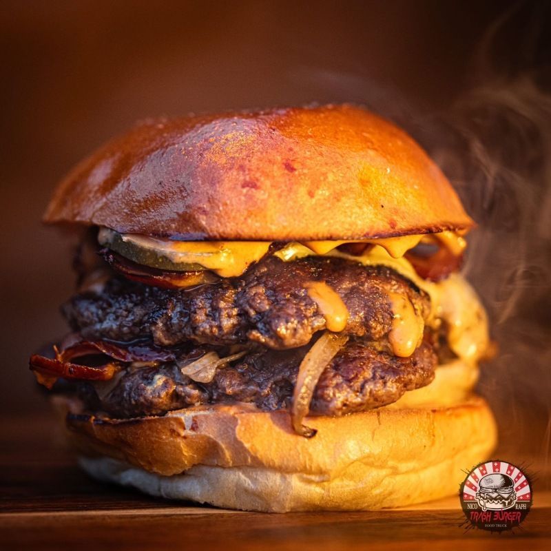 Un double cheeseburger est posé sur une table en bois avec de la fumée qui en sort.
