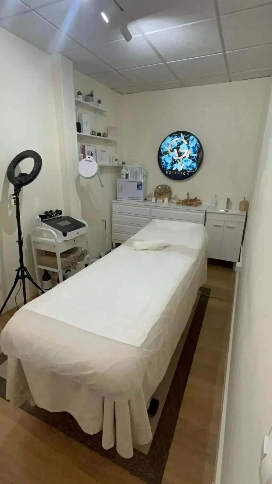 Sala de spa con varias máquinas de tratamientos faciales y camilla de masaje. Paredes beige.