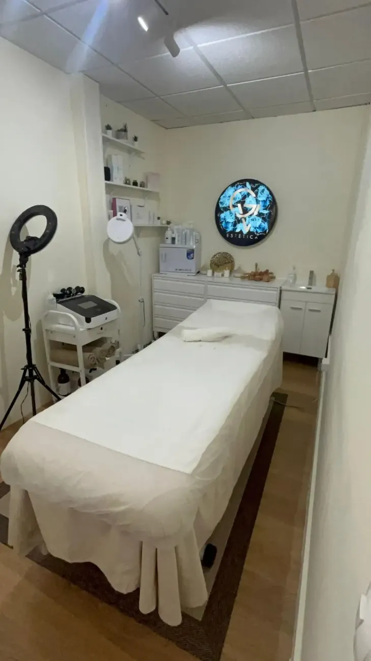 Sala de spa con varias máquinas de tratamientos faciales y camilla de masaje. Paredes beige.