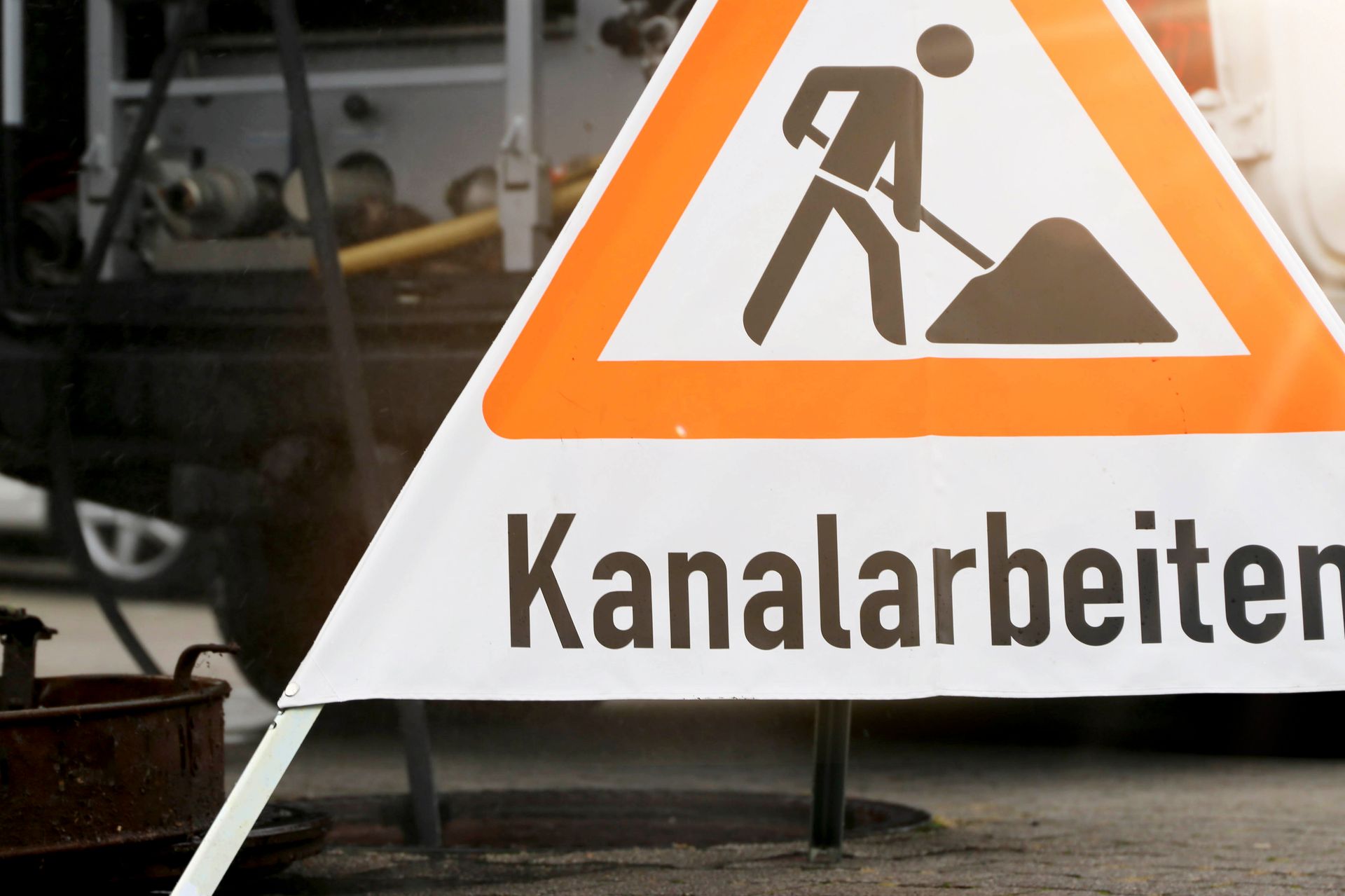 Orangefarbenes dreieckiges Verkehrsschild „Kanalarbeiten“, Mann gräbt.