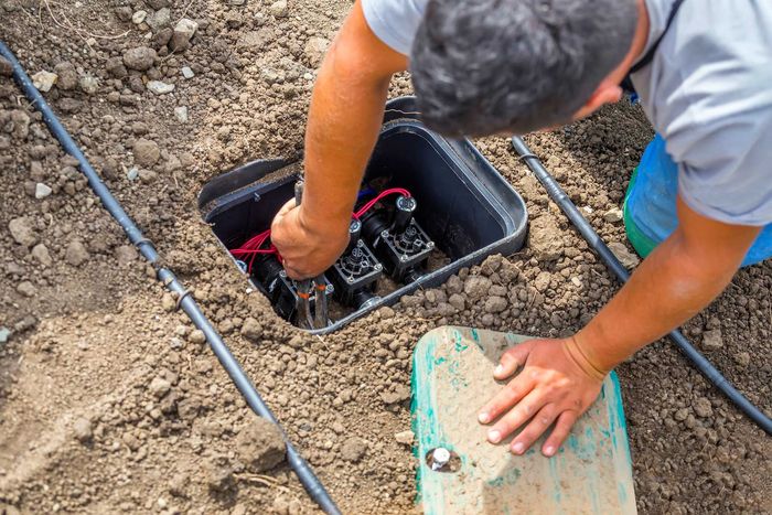 Un ouvrier intervenant sur un panneau de raccordement d'irrigation