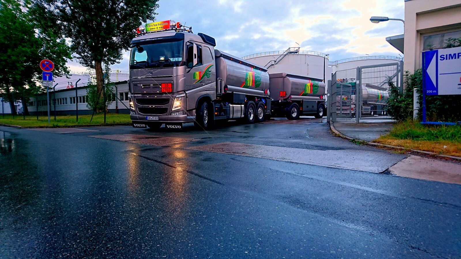 An einem bewölkten Tag fährt ein Tanklastwagen mit zwei Anhängern in ein feuchtes Industriegebiet ein.
